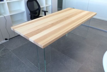 Tavolo in legno con gambe in vetro.